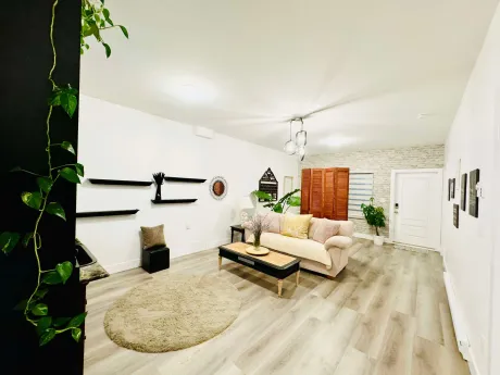 The lounge with a cream sofa, low table and plants beside a bright window