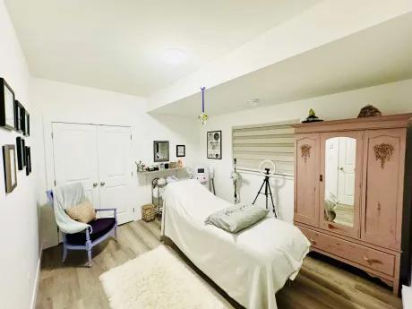 The treatment room with a draped treatment bed, sheepskin rug and antique wooden armoire